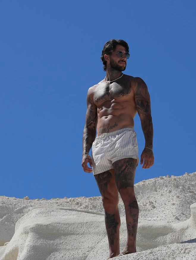 The coach is posing on the sand.